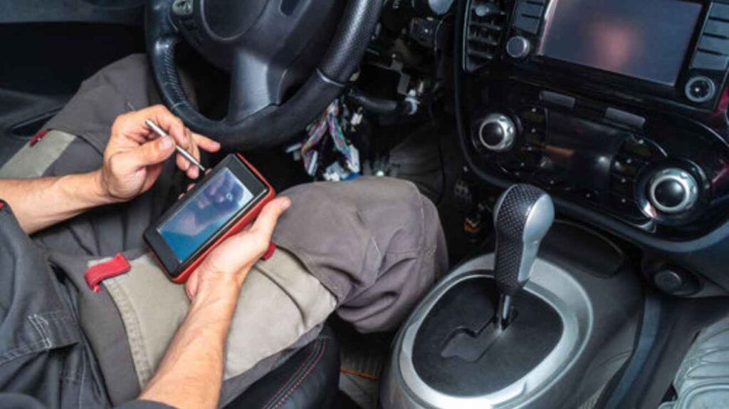 Professional mechanic using OBD scanner to diagnose car smell issues.