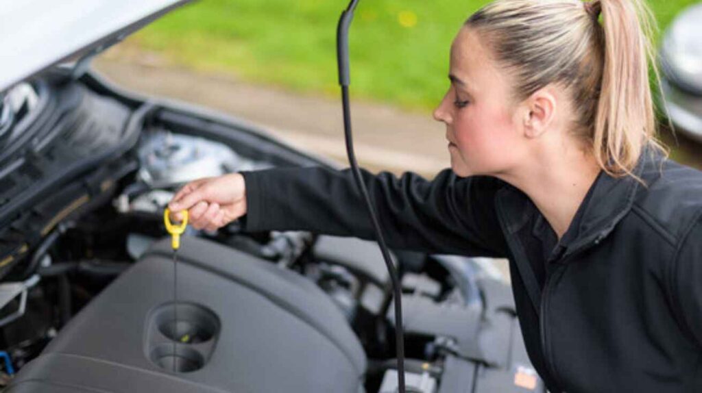 Checking car oil level on dipstick before adding oil carefully