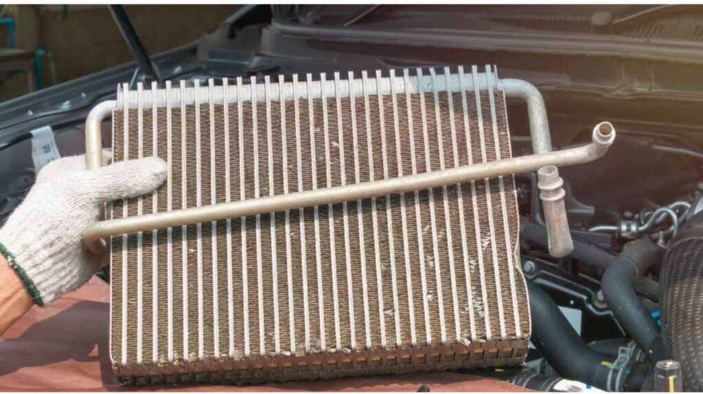 Dirty car condenser behind grille blocked with dust and debris causing poor cooling.