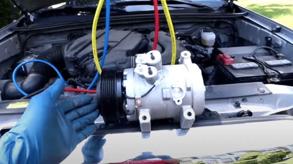 Technician inspecting faulty AC compressor in car engine bay with tool in hand.
