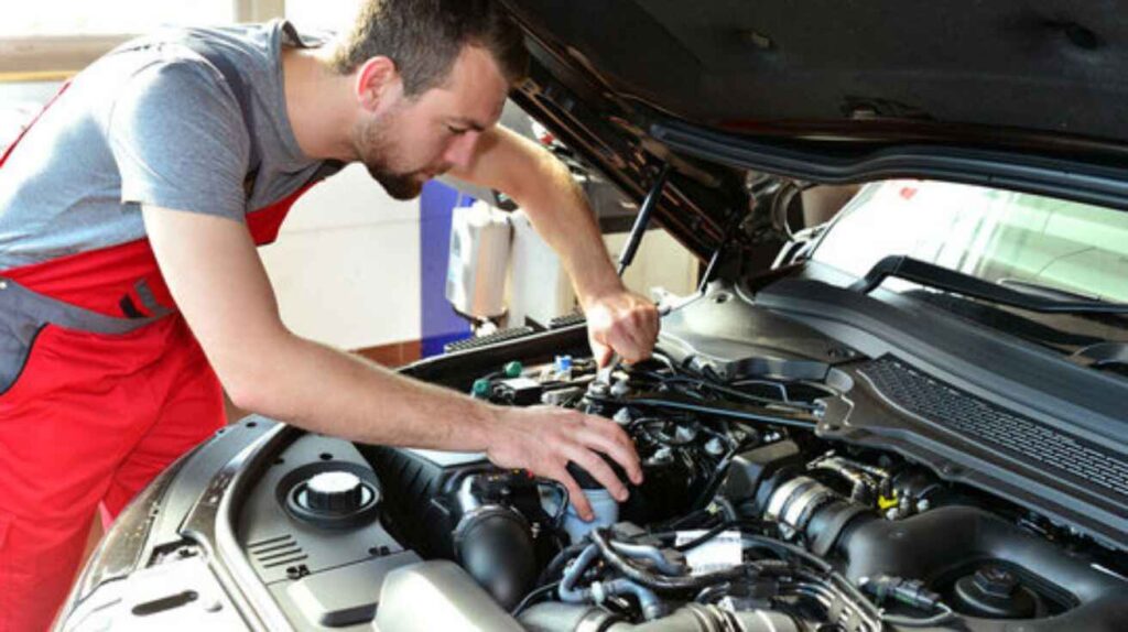 Mechanic inspecting engine oil and fluids as part of vehicle maintenance check.