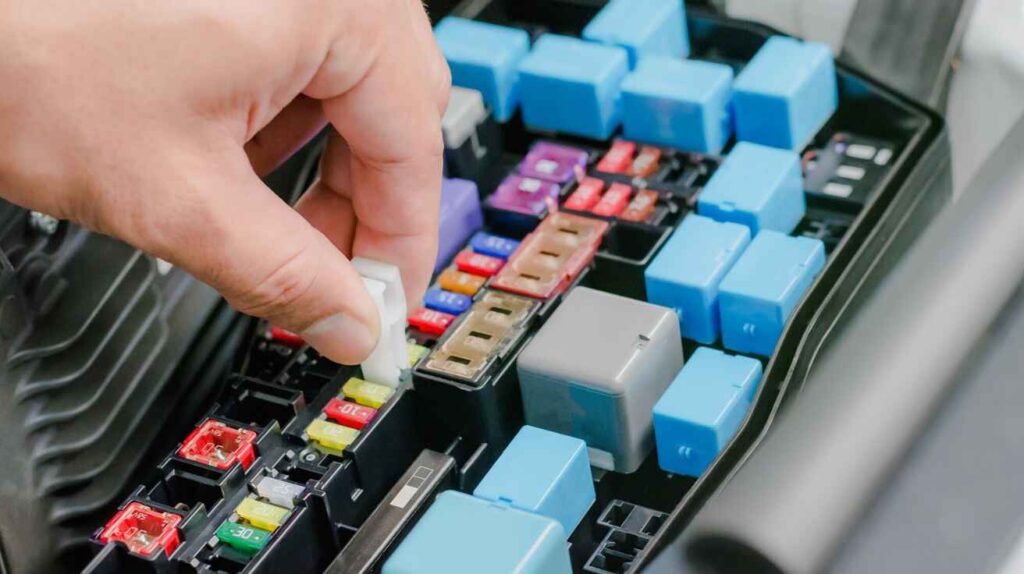 Car relay being inspected inside fuse box for lighting issues.