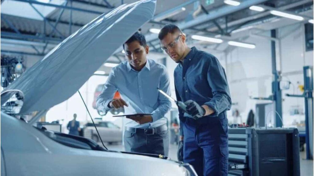 Professional mechanic inspecting car AC system for automatic activation issues and discussing with car owner.