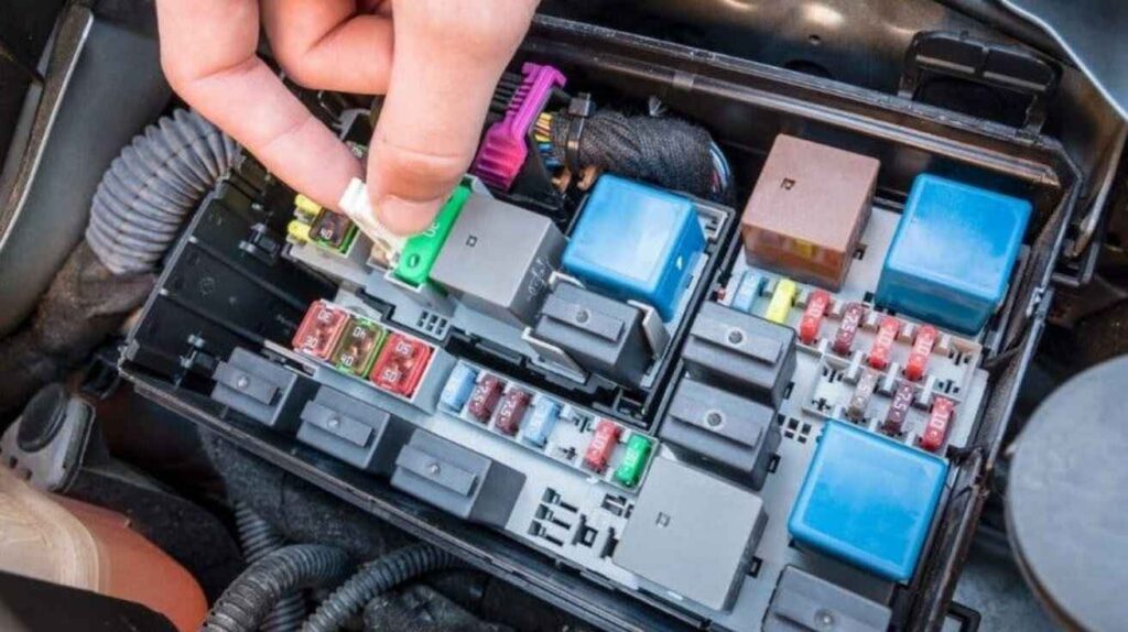 Mechanic checking and replacing faulty AC relay in car fuse box.