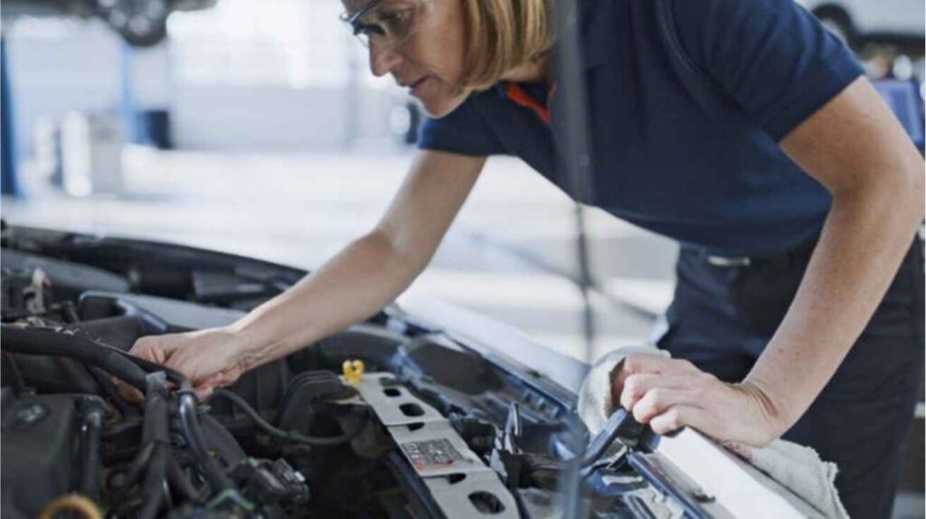 Mechanic inspecting car dashboard and interior to diagnose source of liquid sloshing sound.