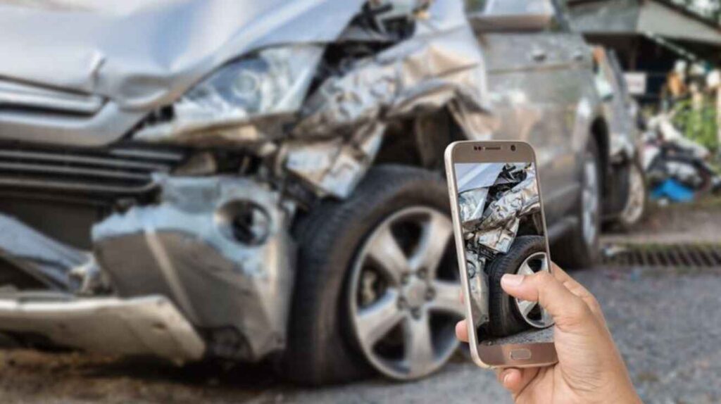 A person photographing car damage after an accident.